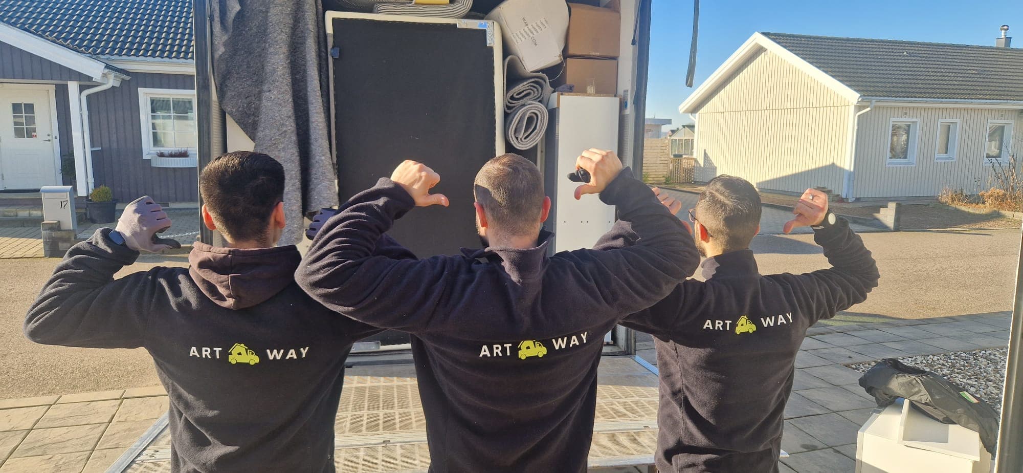 Tre Artway-medarbetare i arbetskläder framför en lastad flyttbil
